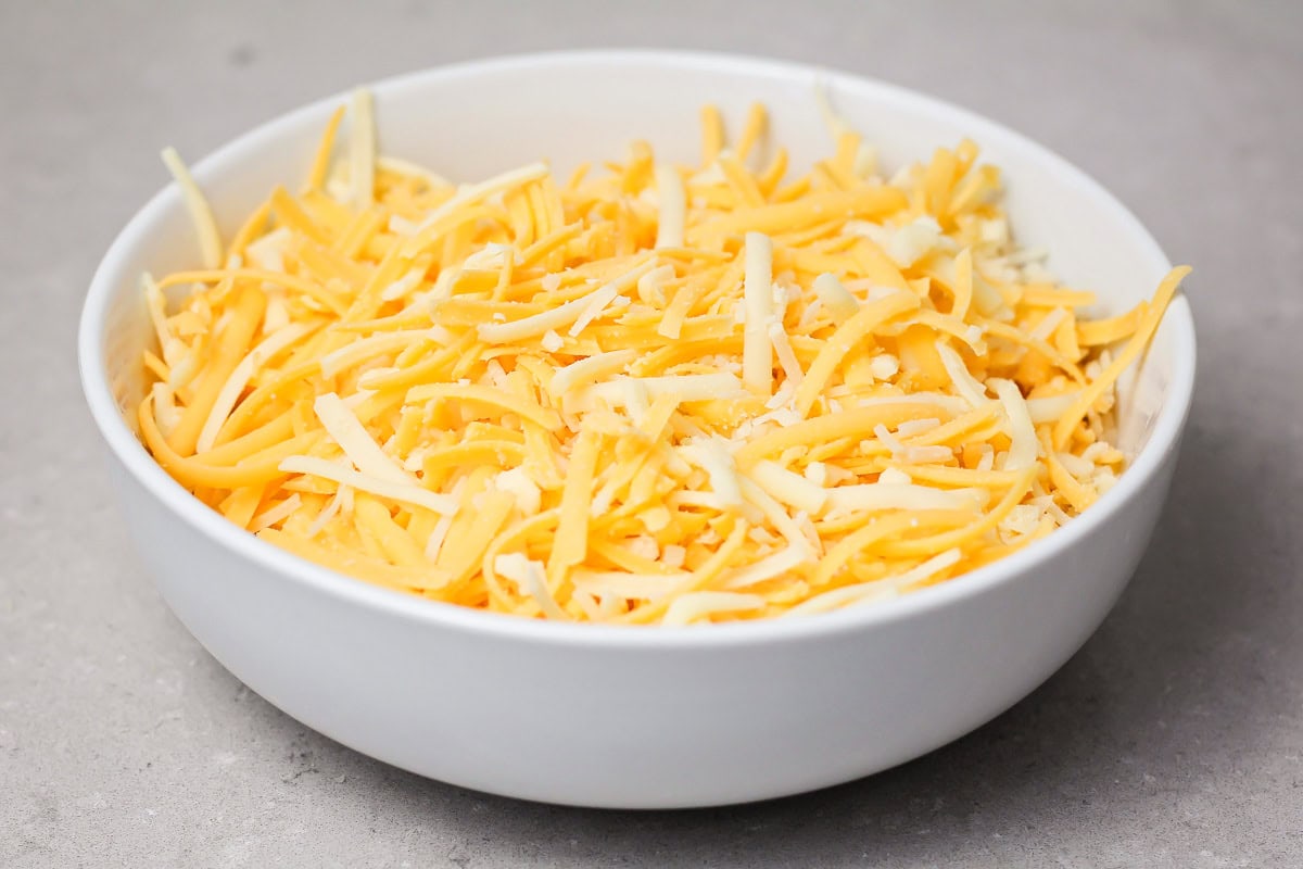 Shredded cheese in a white bowl.