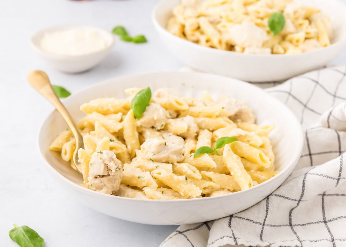 A white bowl of chicken penne pasta.