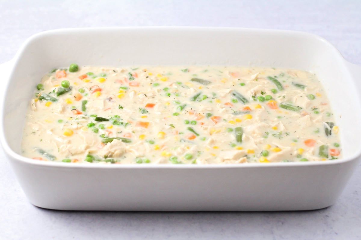 Veggie mixture in the bottom of a white baking dish.