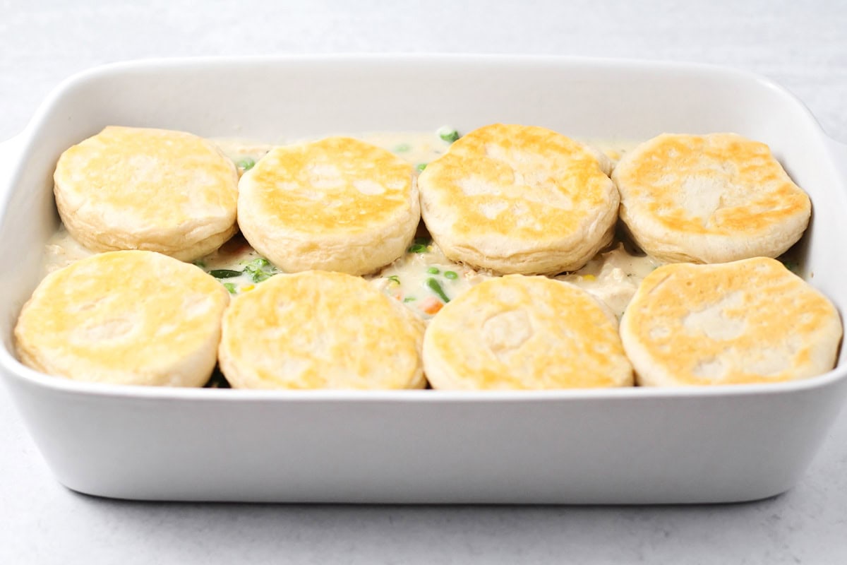 Topping the veggie mixture with baked biscuits.