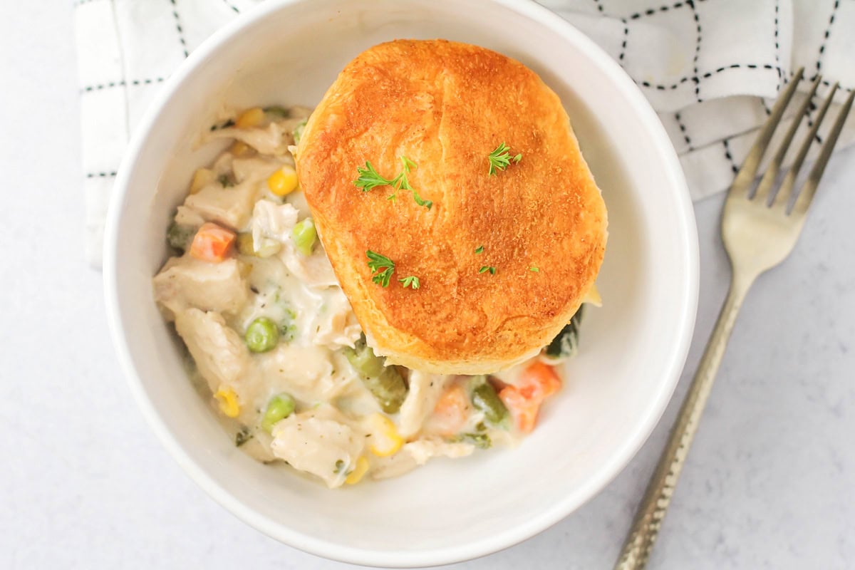 A bowl of chicken pot pie casserole topped with a biscuit.