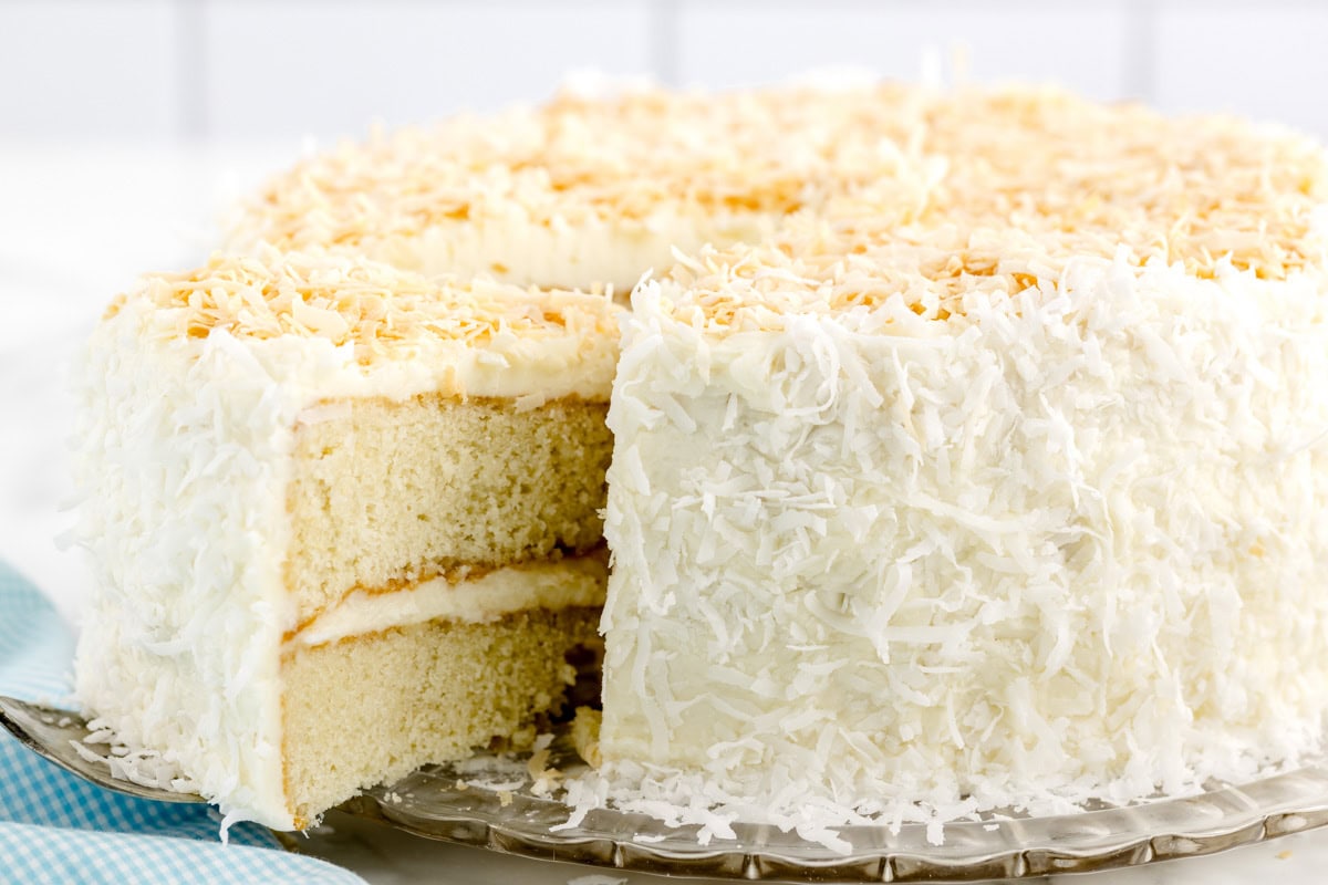 Coconut frosting on coconut cake with slice being dished out.
