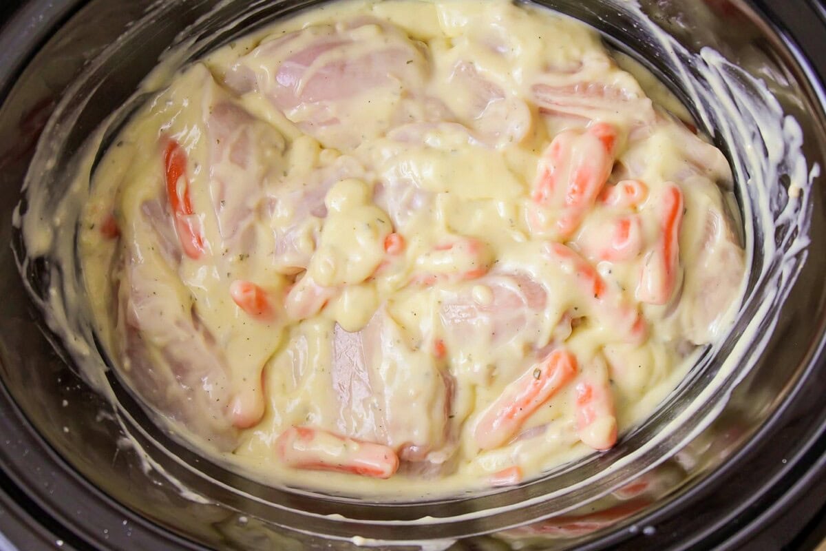 Chicken breast, carrots, and cream of chicken soup mixed in a crockpot.