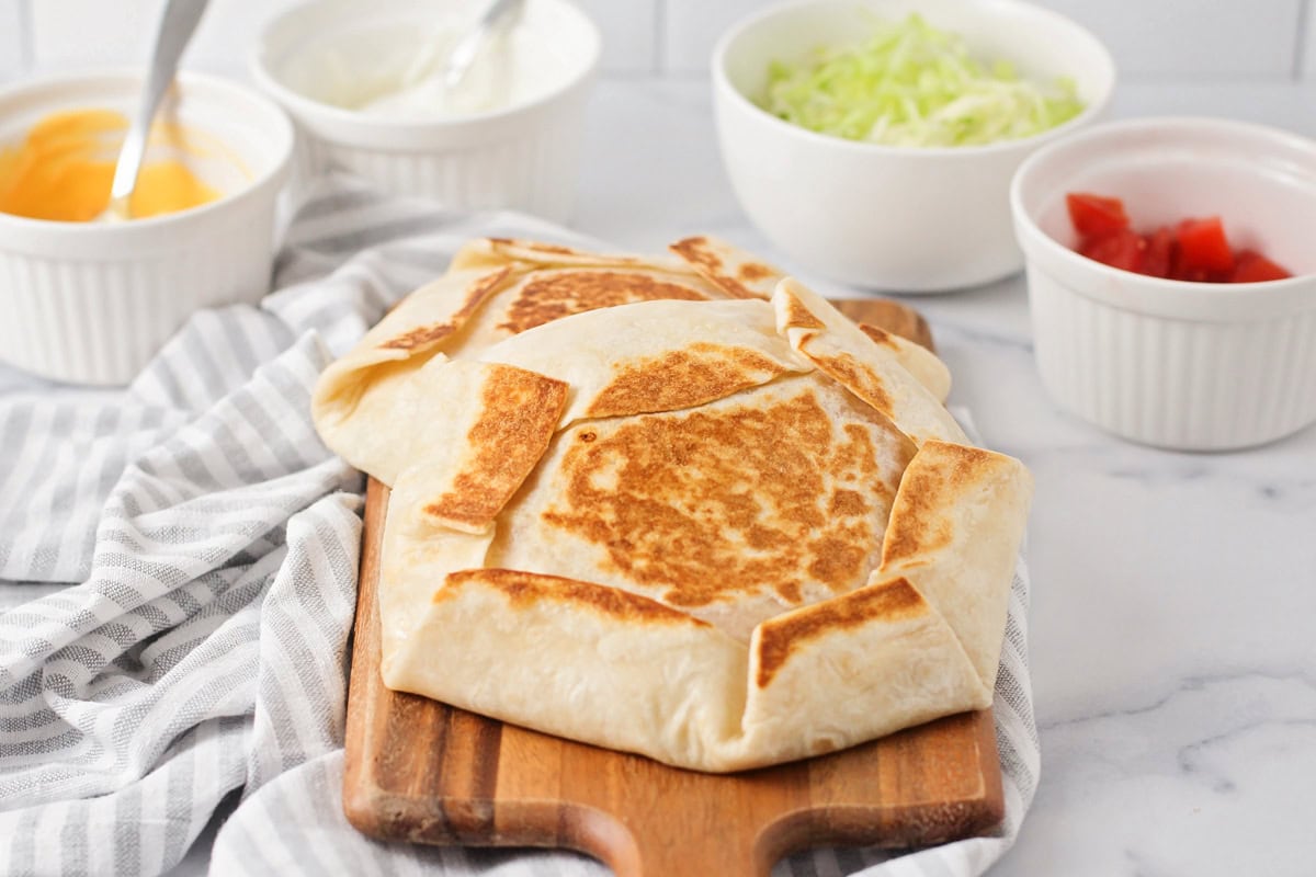 Two crunchwrap supremes on a cutting board.