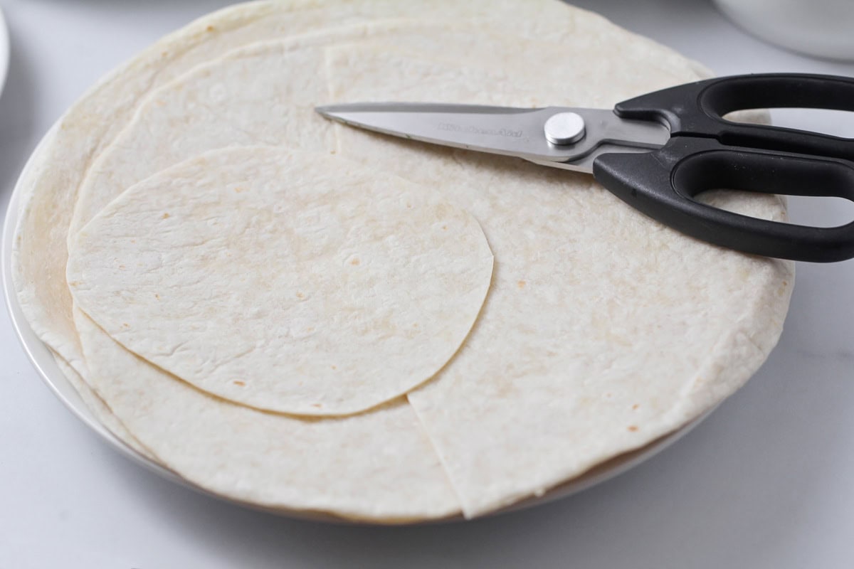 Cutting tortillas into smaller circles.