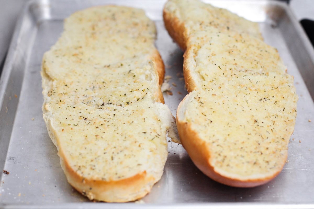 Butter melted into halved french bread on a baking sheet.