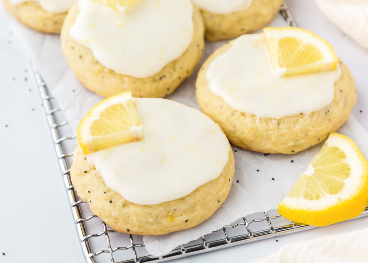 Several frosted lemon poppy seed cookies on a cooling rack.