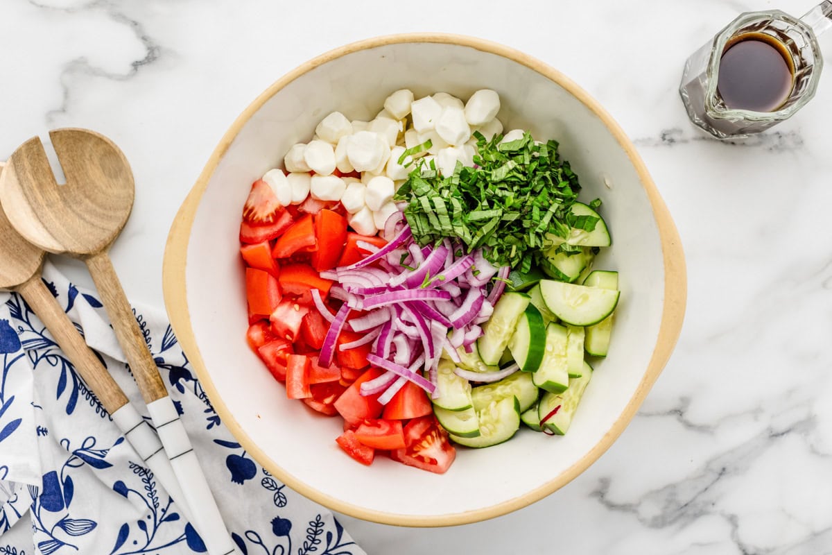 Veggies and herbs chopped in a bowl on a kitchen counter.