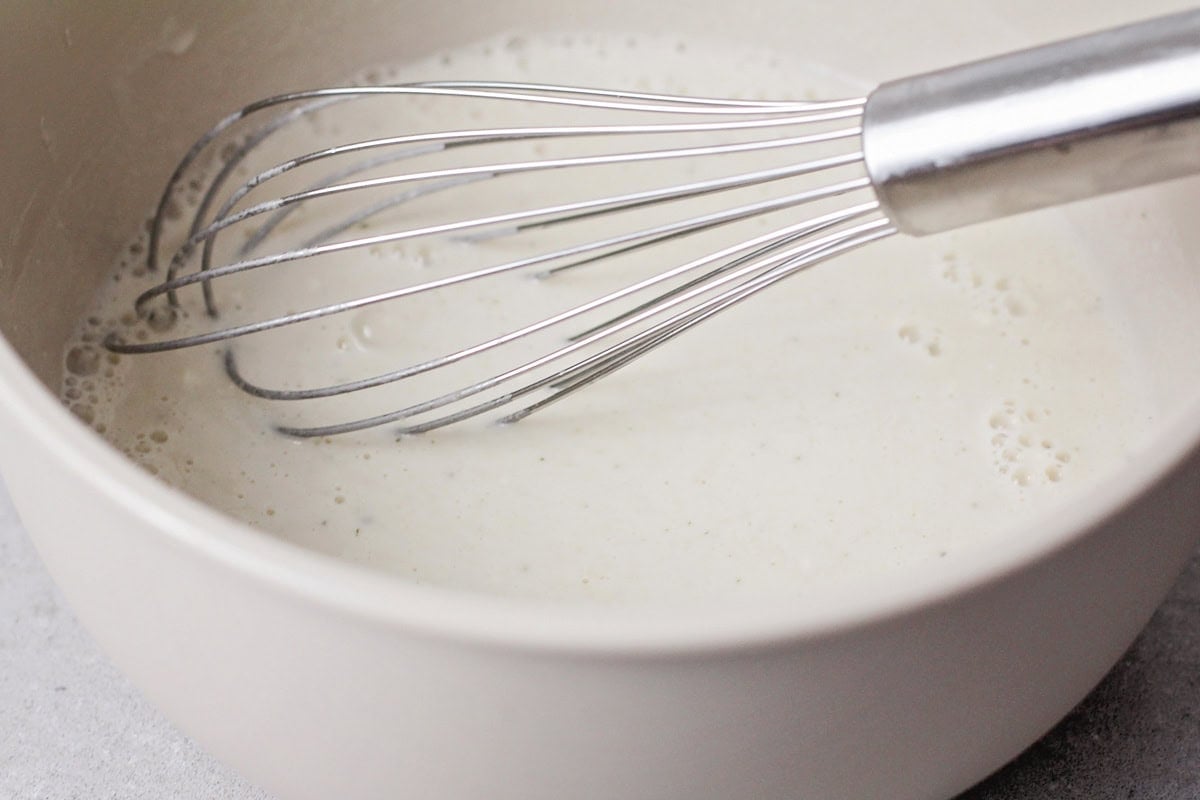 Whisking milk mixture in a grey bowl.