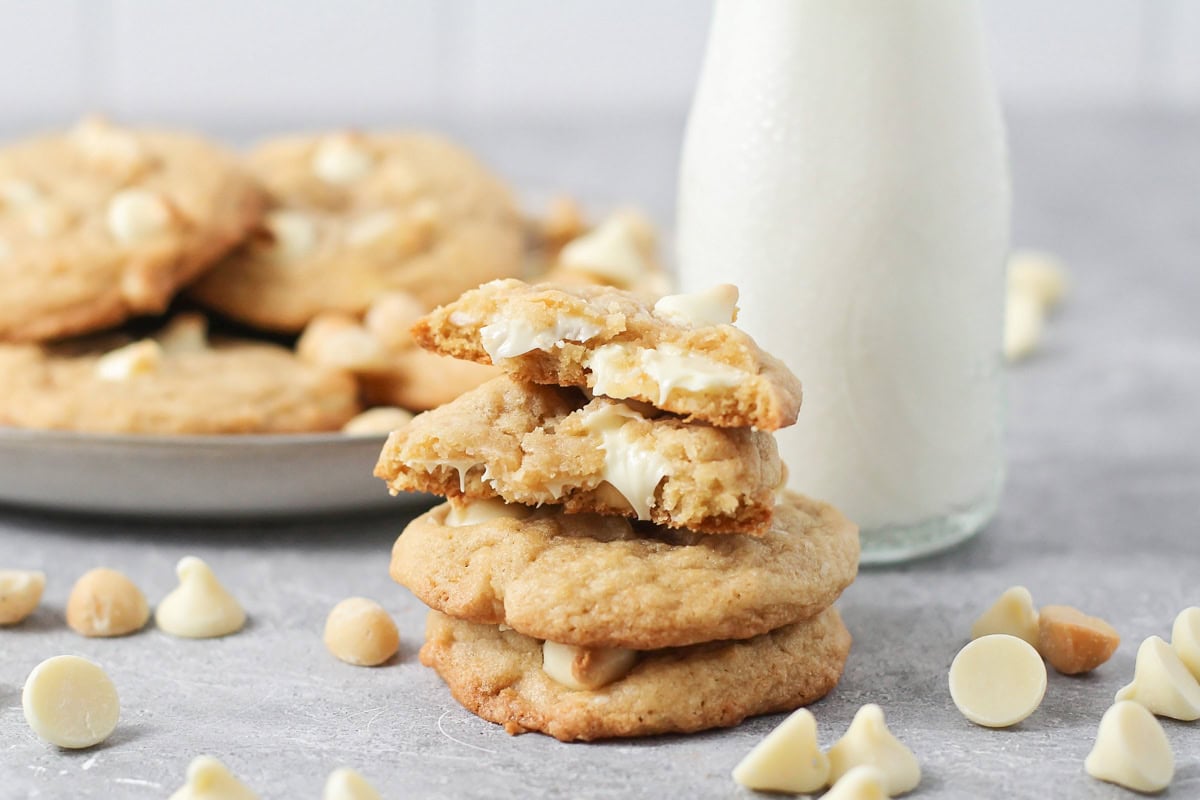 A stack of white chocolate macadamia nut cookies with one broken in half.