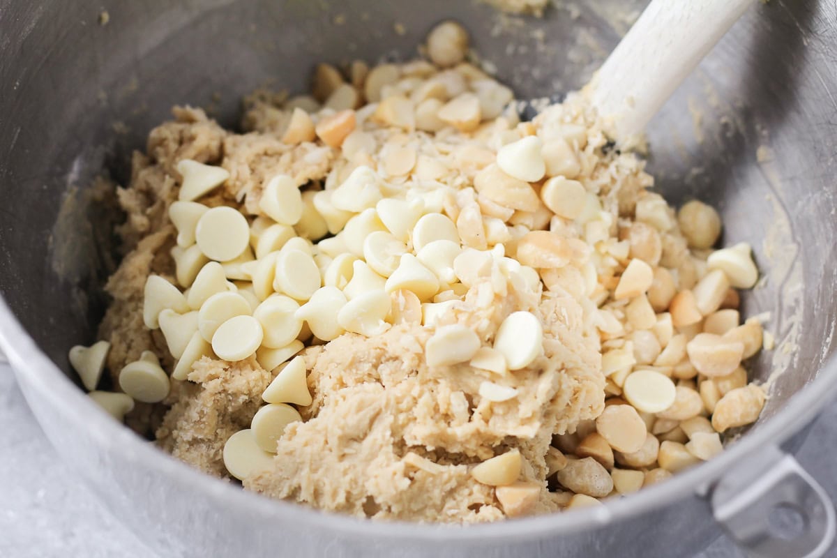 Adding white chocolate chips to cookie dough.