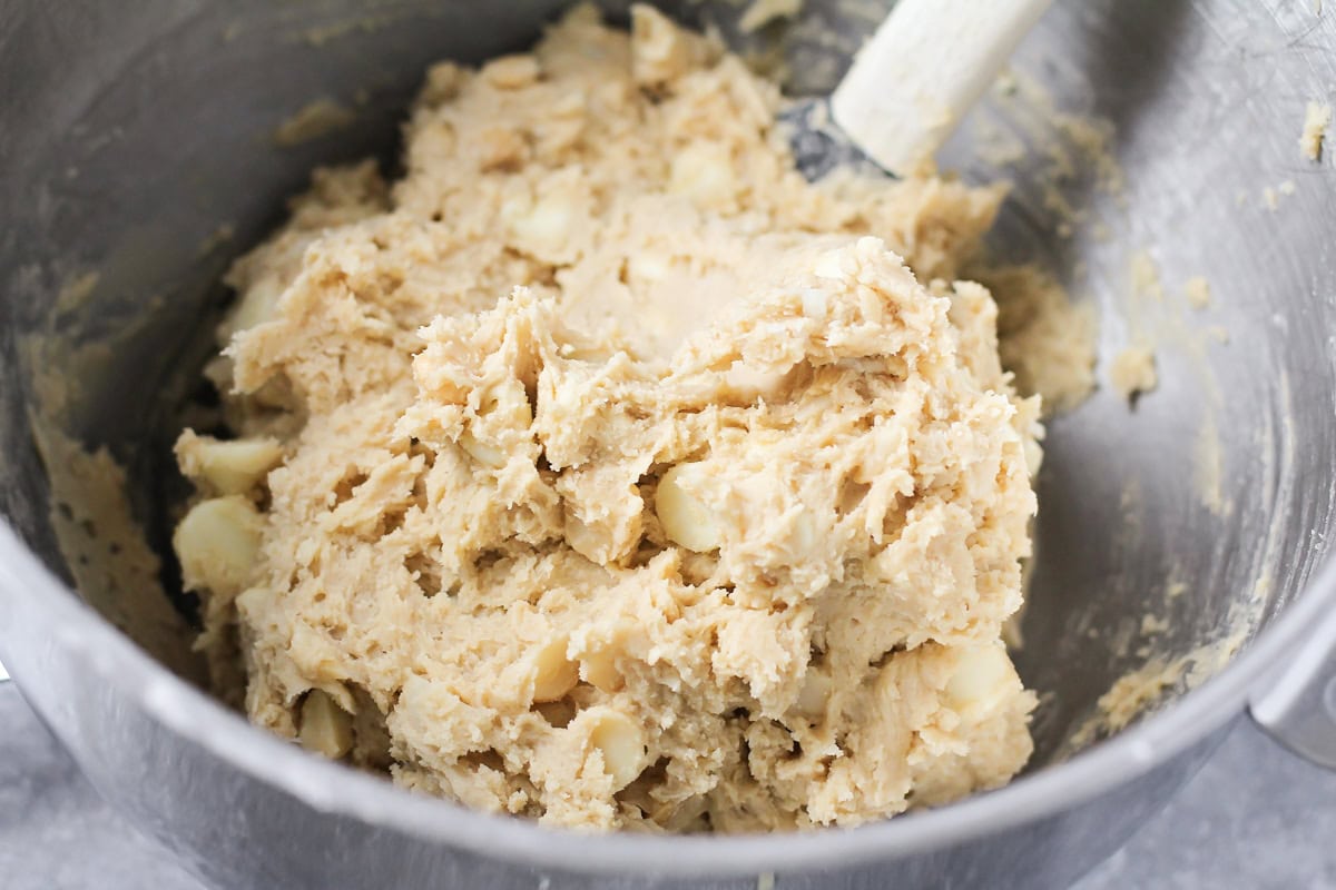 Mixing white chocolate chips into cookie dough.