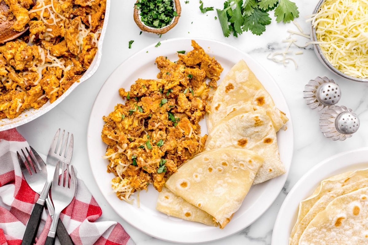 Chorizo and eggs recipe on plate with  folded flour tortillas.