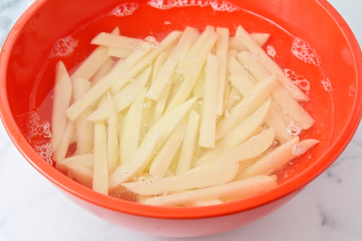 Soaking cut potatoes in water for homemade french fries.