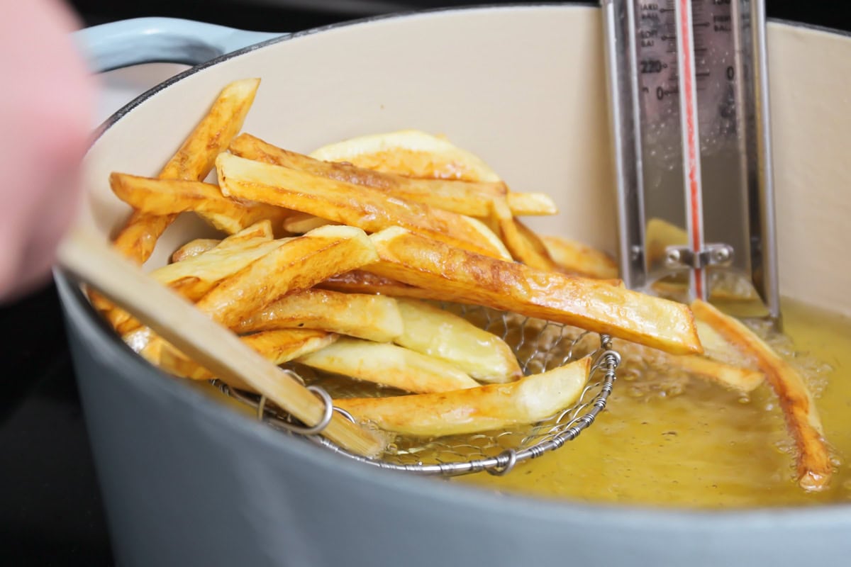 Homemade french fries being taken out of oil.