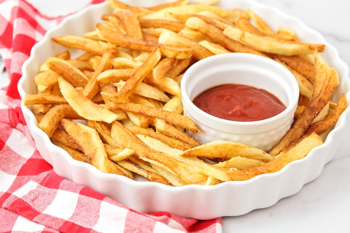 Homemade french fries with ketchup in dish.