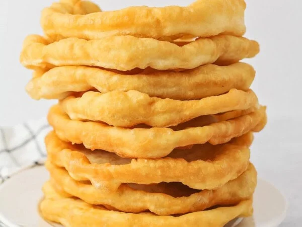 Homemade fry bread recipe all stacked on top of each other on white plate.