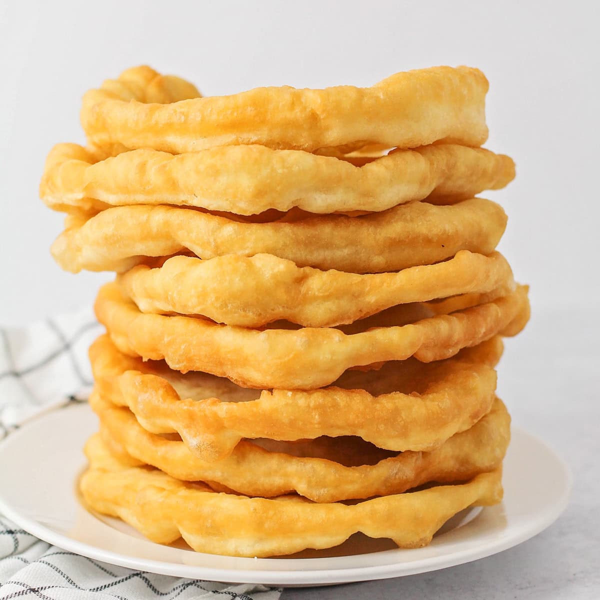 Fry bread stacked on top of each other on white plate.