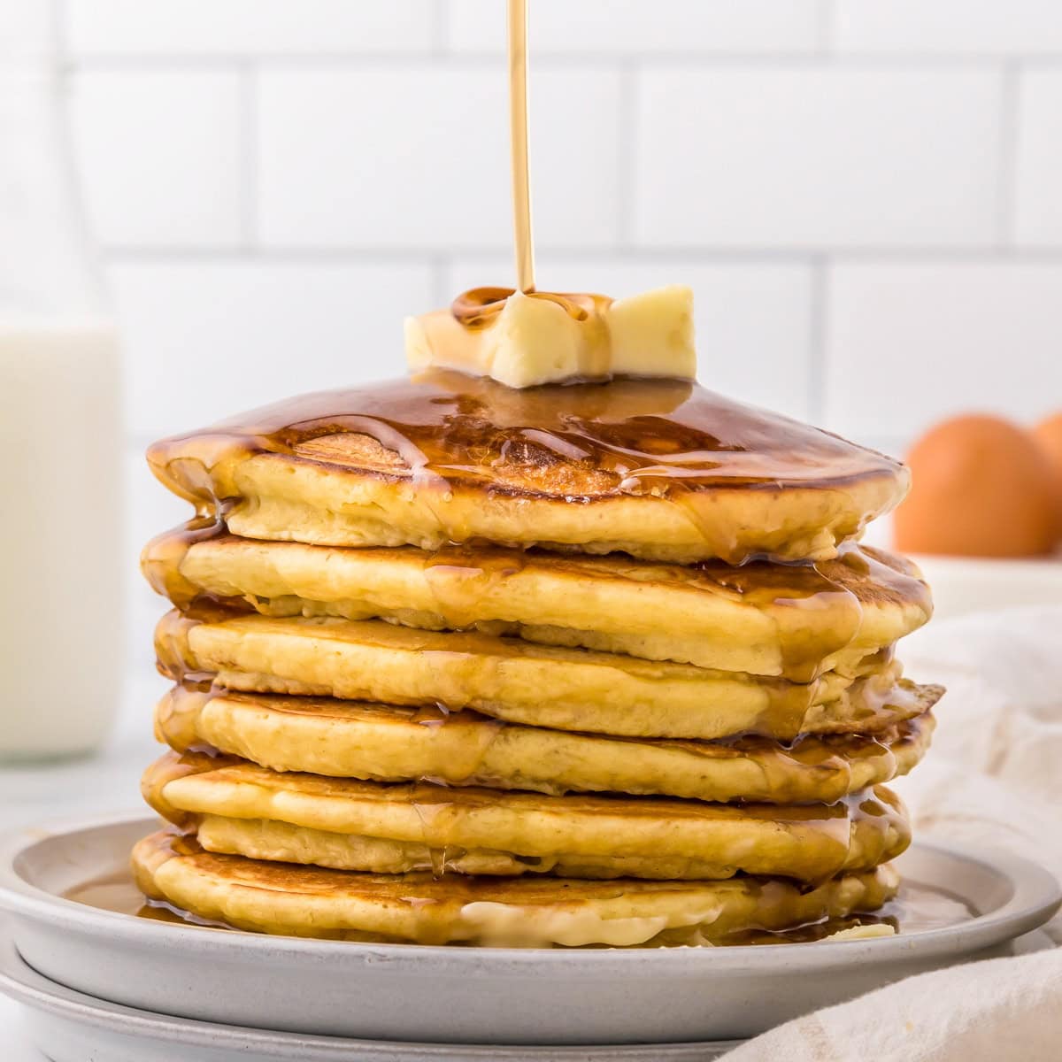 Picture of pancakes stacked with homemade syrup being poured over them.