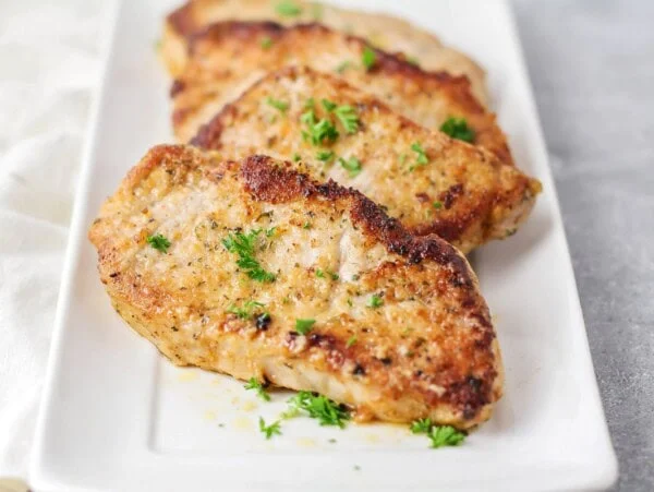 Parmesan crusted pork chops served on a white platter.