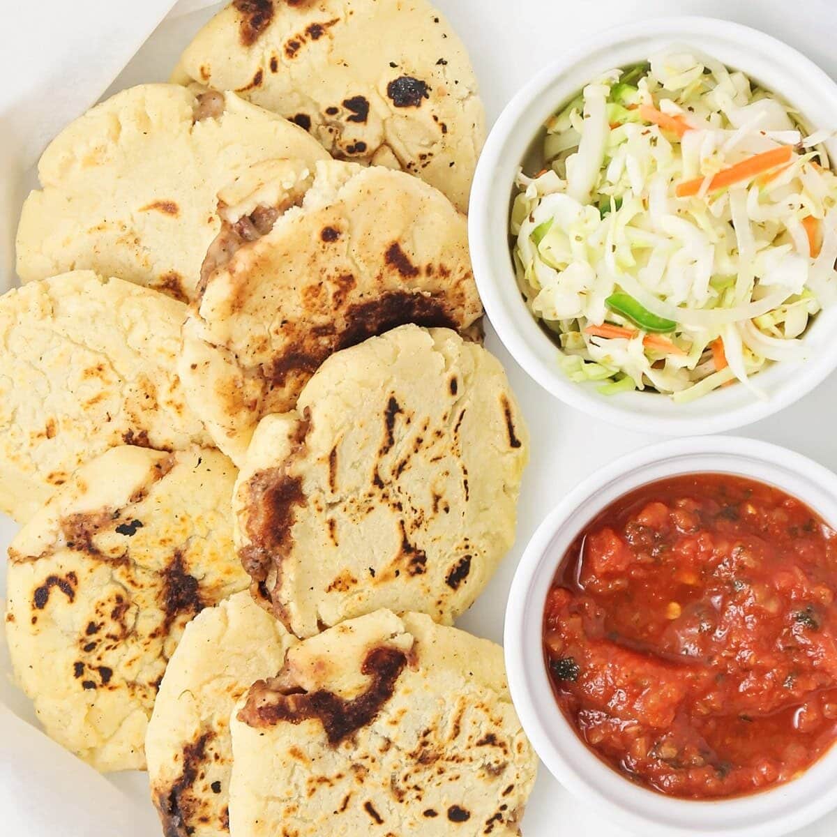 Pupusas layered together in white dish.