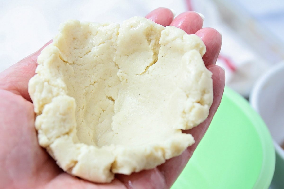 Pupusas dough cupped together in hands.