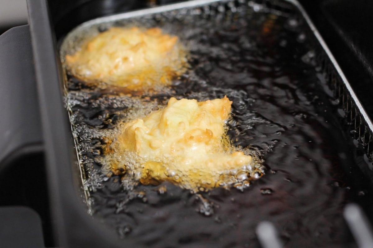 Frying apple fritters in oil.