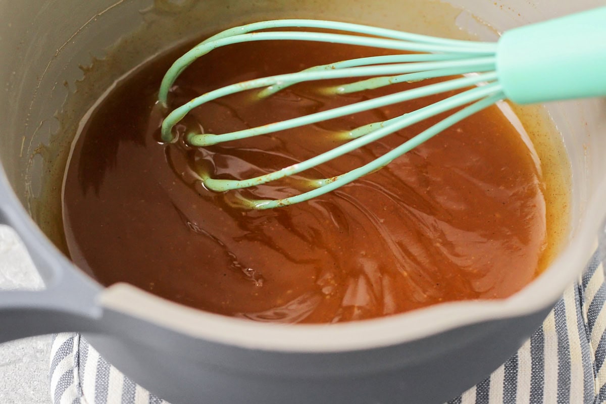 Mixing spiced apple sauce in a stove on the pan.