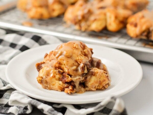 Baked pumpkin fritter with glaze on top on white plate.