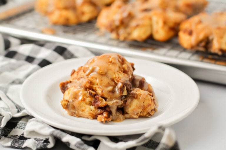 Baked pumpkin fritter with glaze on top on white plate.