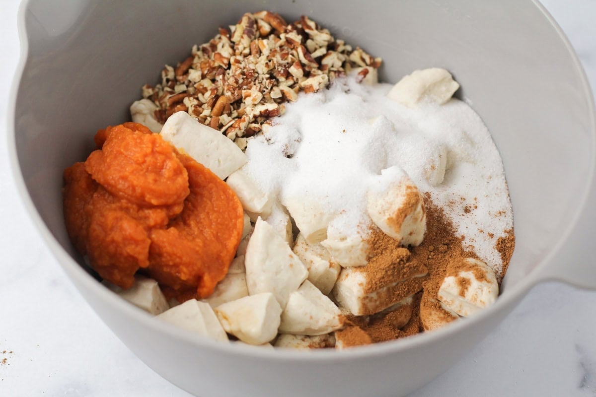 Adding seasonings and pumpkin puree to cut biscuits.