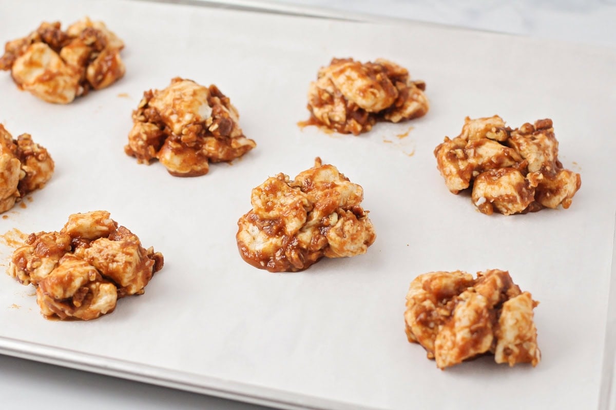 Placing scoops of biscuit dough on a lined baking sheet.