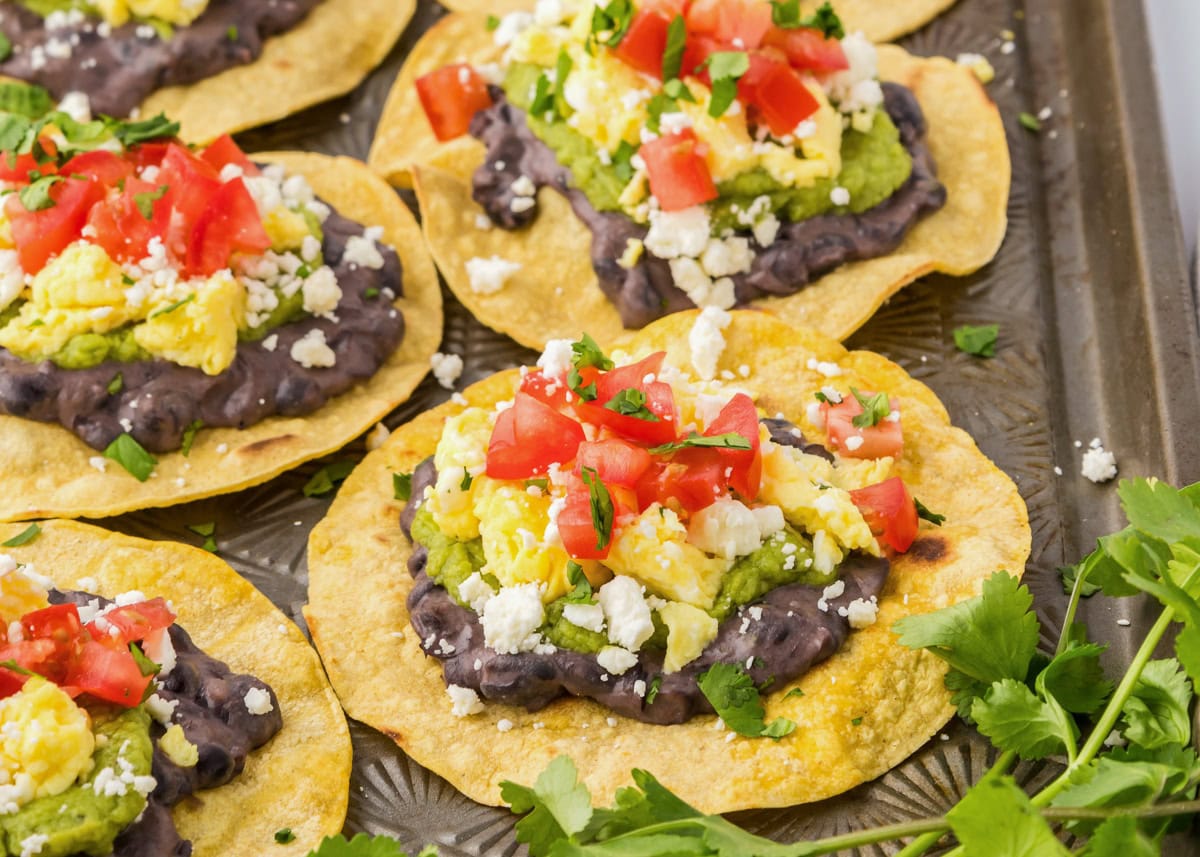 Several breakfast tostadas on a baking sheet.