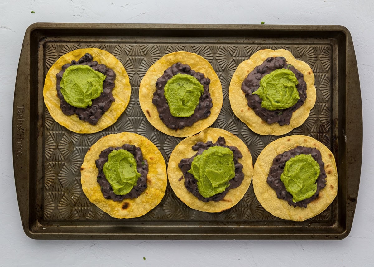 Spreading guacamole on top of the bean mixture.