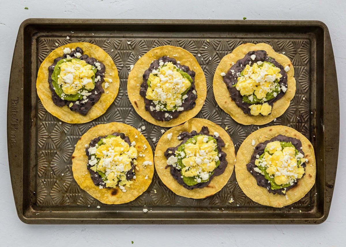 Topping tostadas with scrambled eggs and cheese.