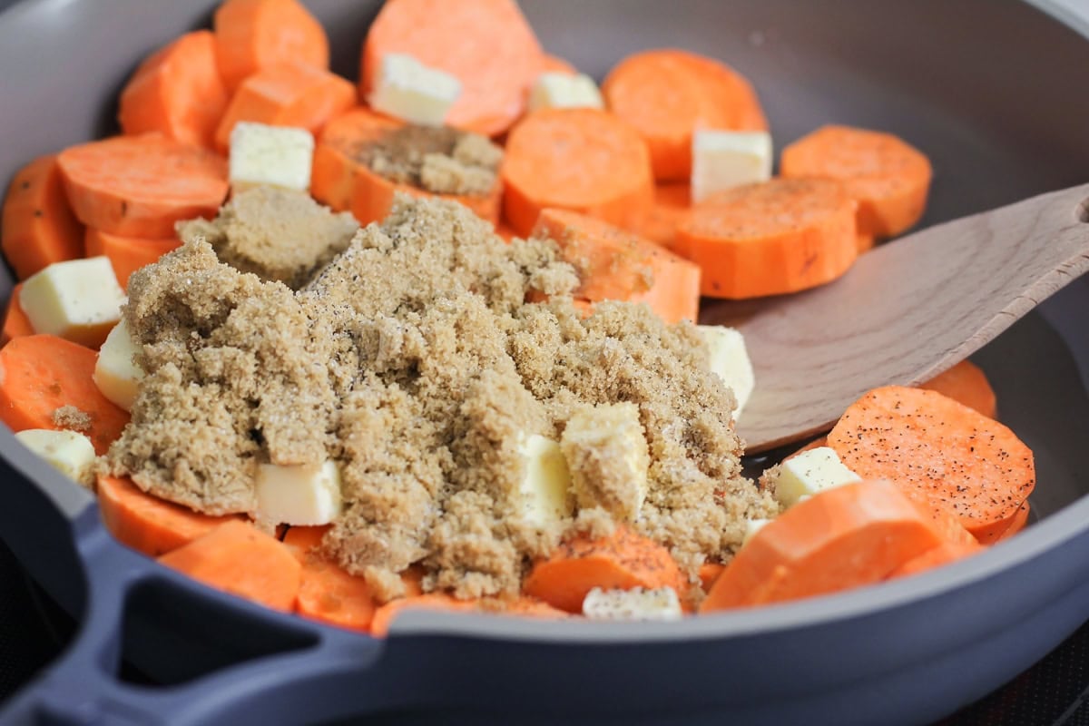 Sliced yams topped with brown sugar and butter in a pan.