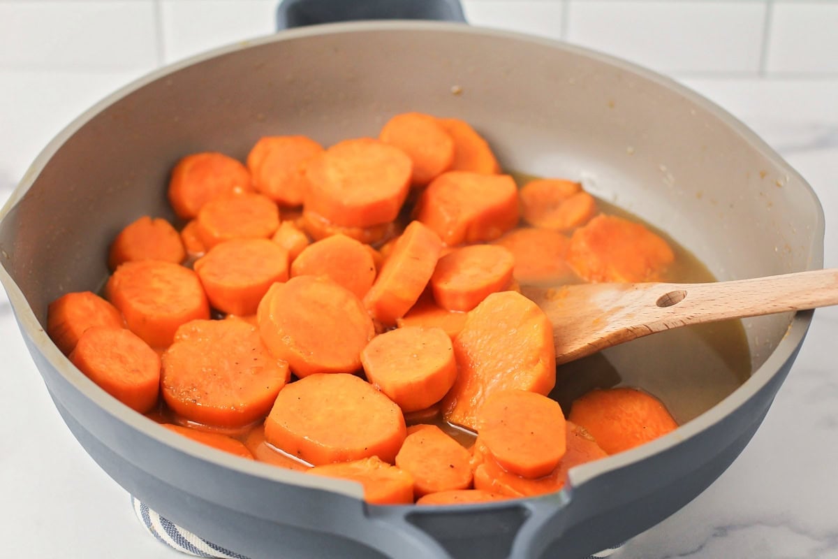 Cooking sliced yams in brown sugar and butter.