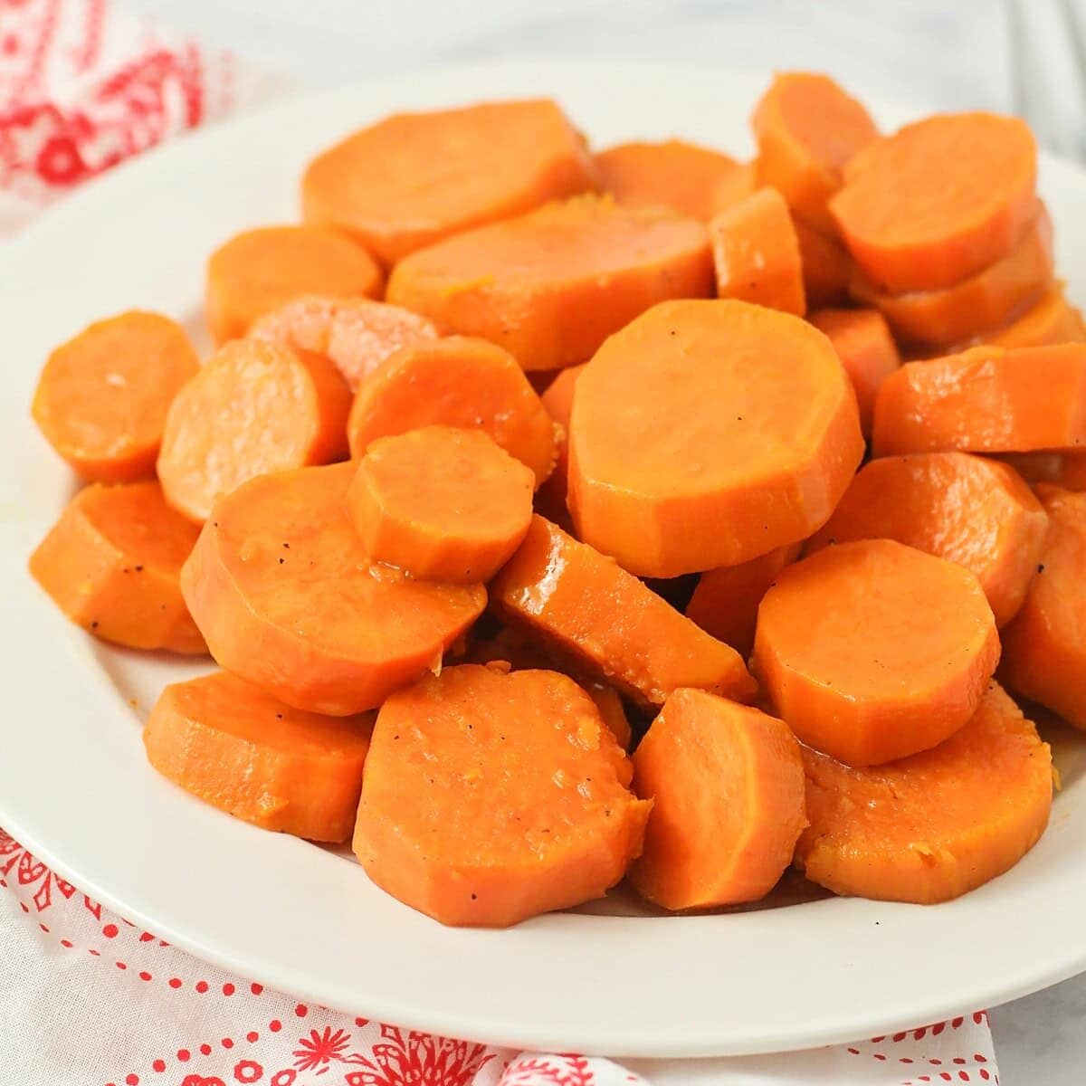 A close up of candied yams in a white bowl.