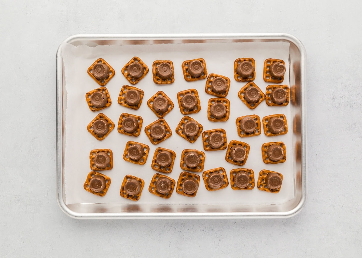 Rolos on top of pretzels on a lined baking sheet.