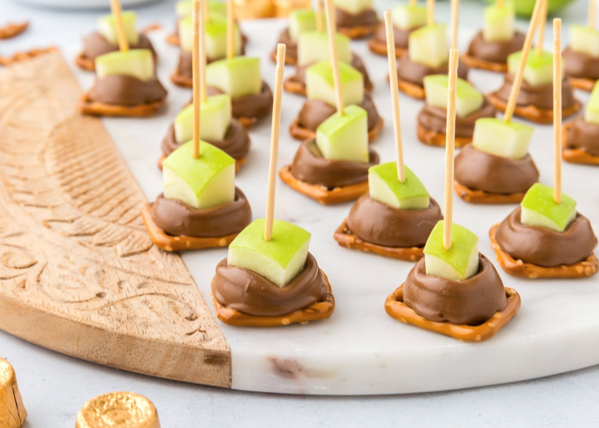 Several caramel apple bites served on a marble platter.