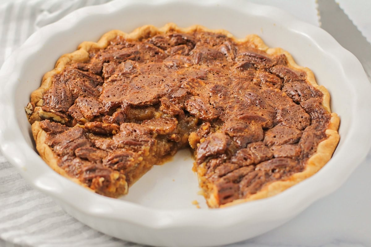 A slice missing from a caramel pecan pie.