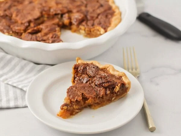 A slice of caramel pecan pie on a plate.