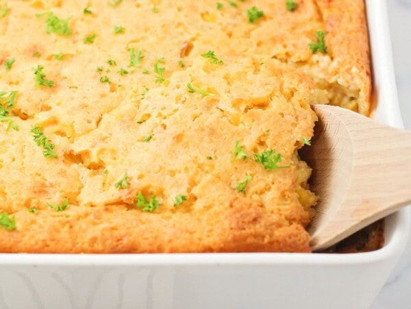 Corn souffle being scooped out of casserole dish.