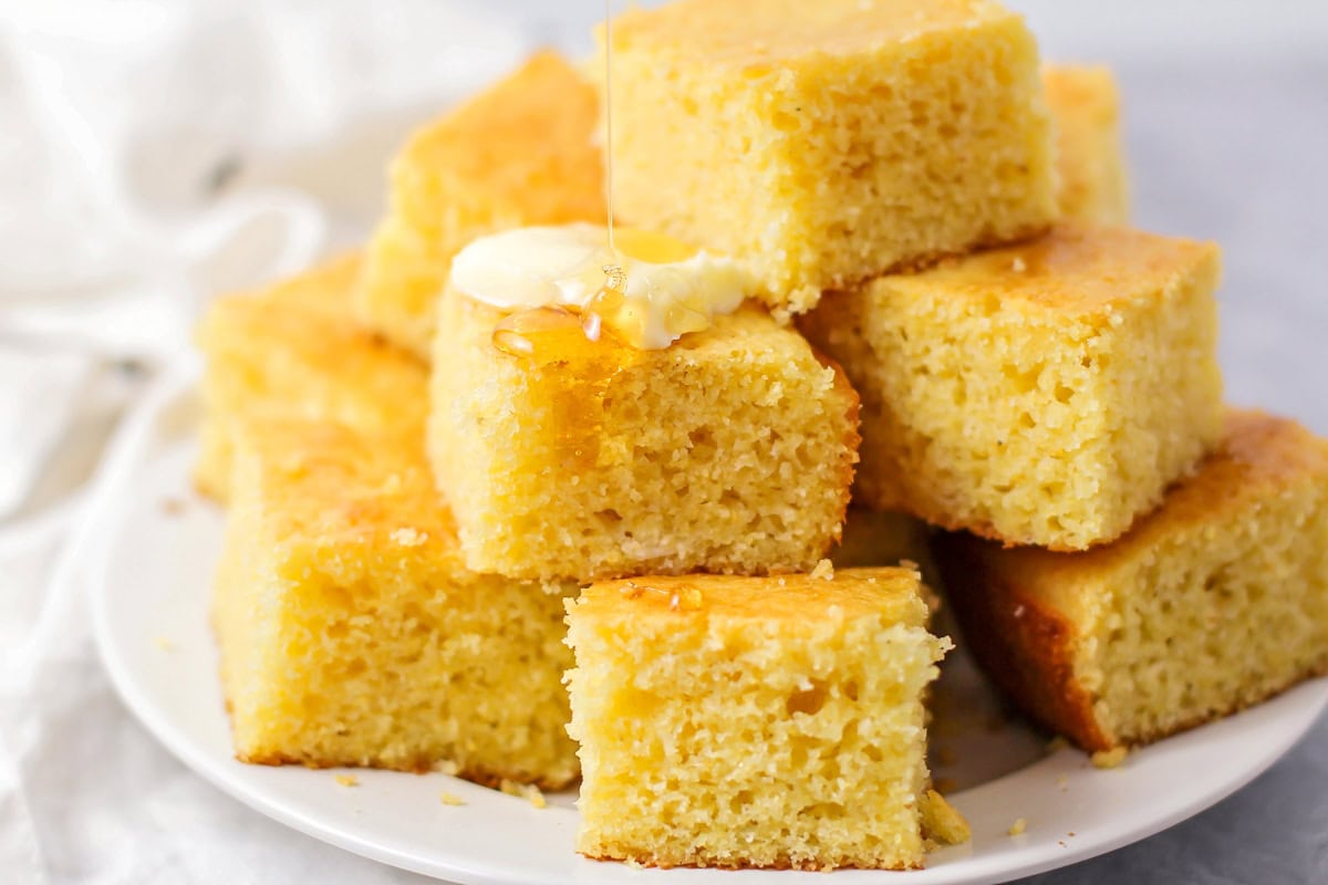 Homemade Cornbread recipe stacked on white plate.