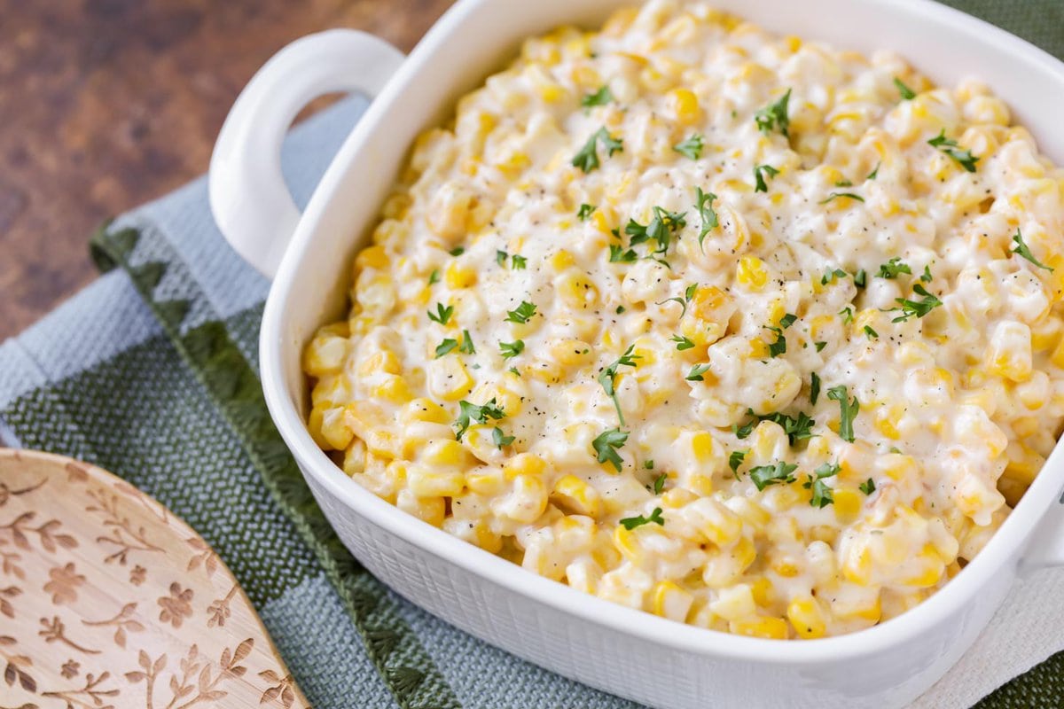 Close up image of creamed corn recipe in white baking dish.