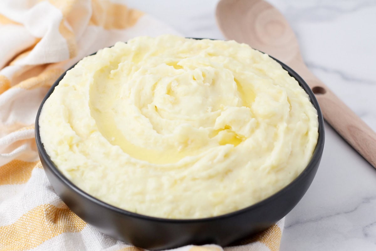 A black bowl filled with garlic mashed potatoes.