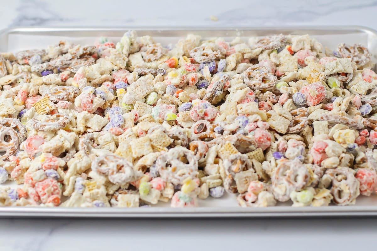 Coated cereal mixture spread on a lined baking sheet.