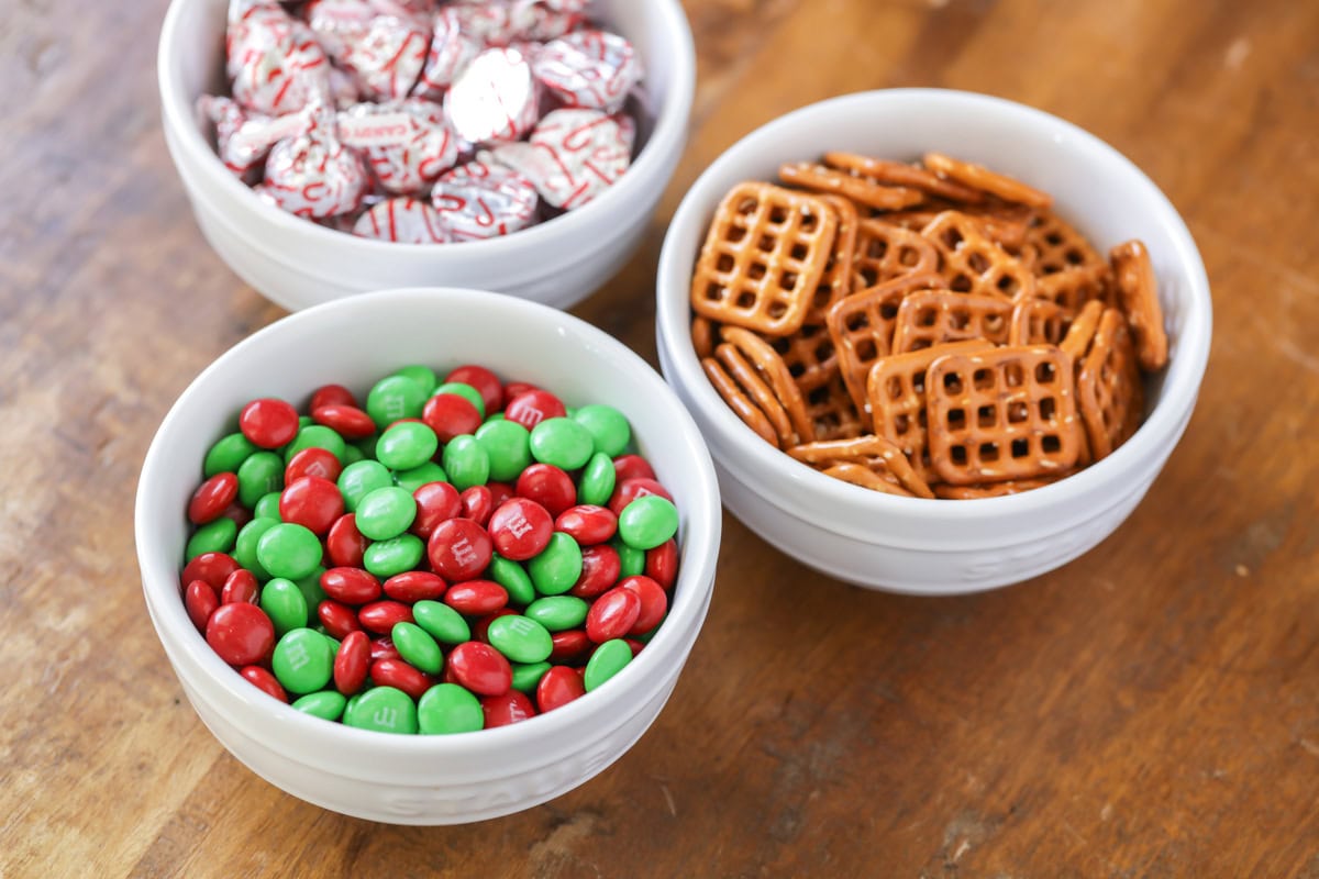 Three bowls of Hershey kisses, pretzels, and holiday m&ms.