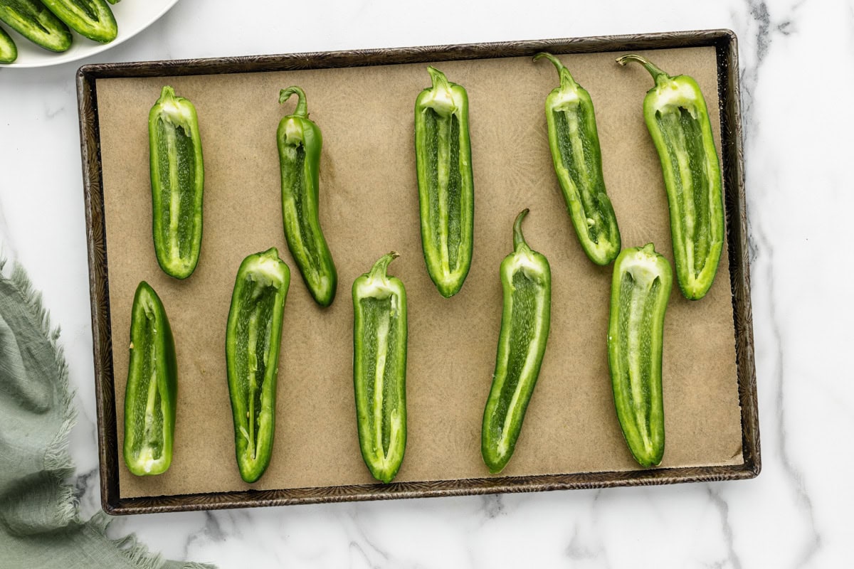 Prepped jalapenos on a baking sheet.