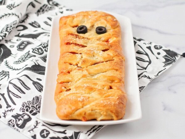 Mummy pizza recipe on white dish.